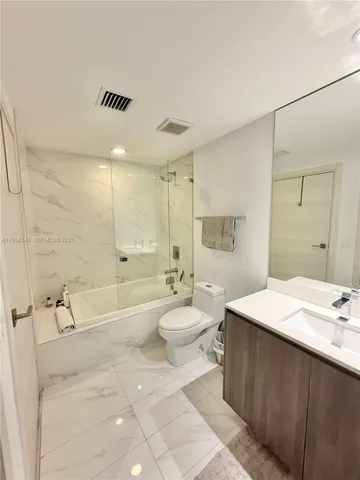 a bathroom with a double vanity sink toilet mirror and bathtub