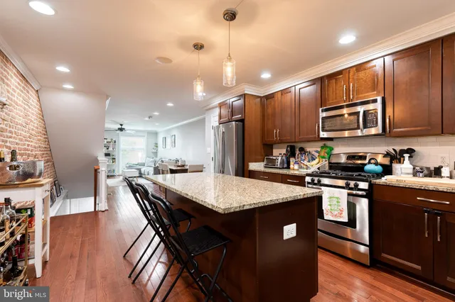 a kitchen with stainless steel appliances granite countertop wooden cabinets a refrigerator a stove a sink and a center island