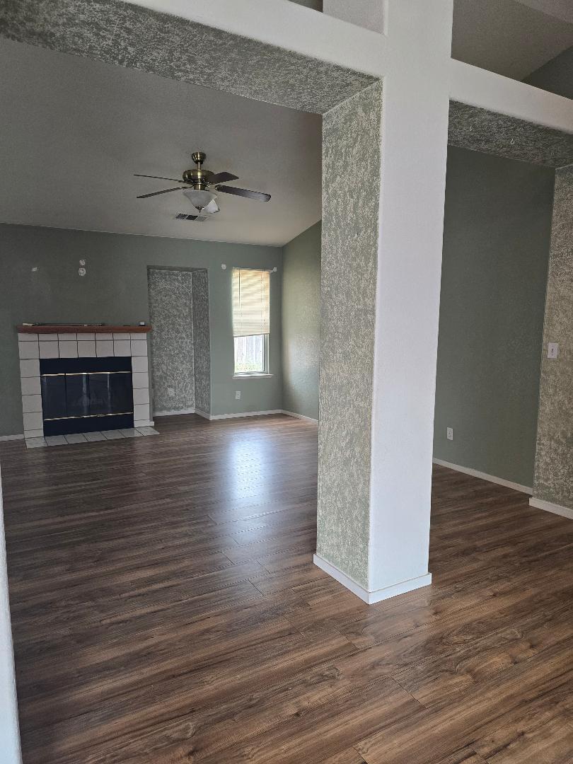 29124 Rio Verde Drive Gustine, CA 95322 - Photo 7 of 19 an empty room with wooden floor fireplace and windows