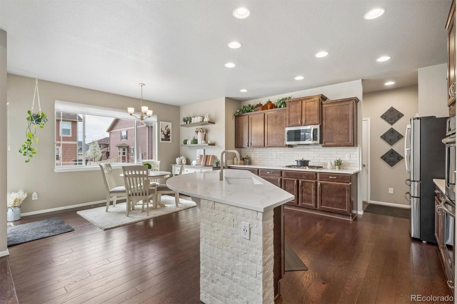 8809 Foxfire Street Firestone, CO 80504 - Photo 11 of 40 a kitchen with stainless steel appliances granite countertop a refrigerator a stove top oven a sink dishwasher and white cabinets with wooden floor