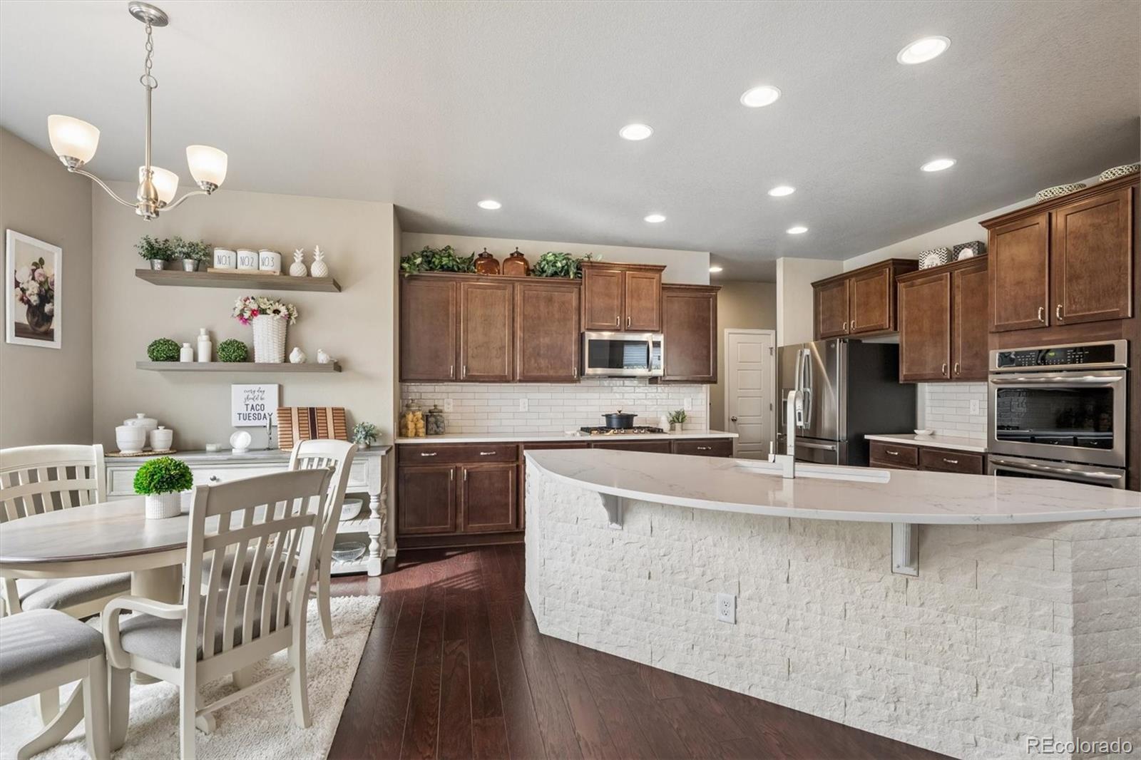 8809 Foxfire Street Firestone, CO 80504 - Photo 13 of 40 a large kitchen with kitchen island granite countertop lots of counter space a sink appliances and cabinets