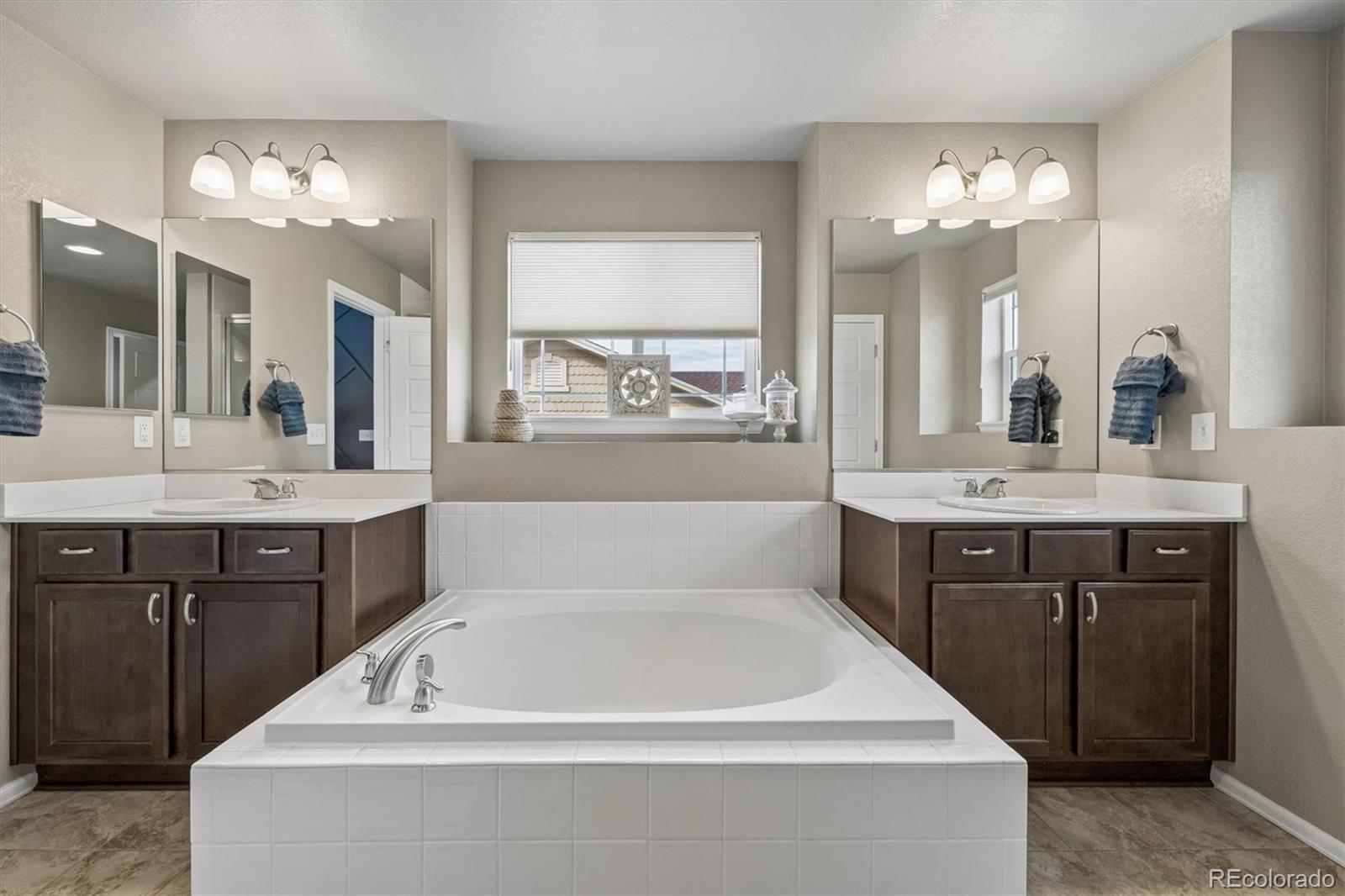 8809 Foxfire Street Firestone, CO 80504 - Photo 18 of 40 a spacious bathroom with a bathtub a double vanity sink a and a mirror