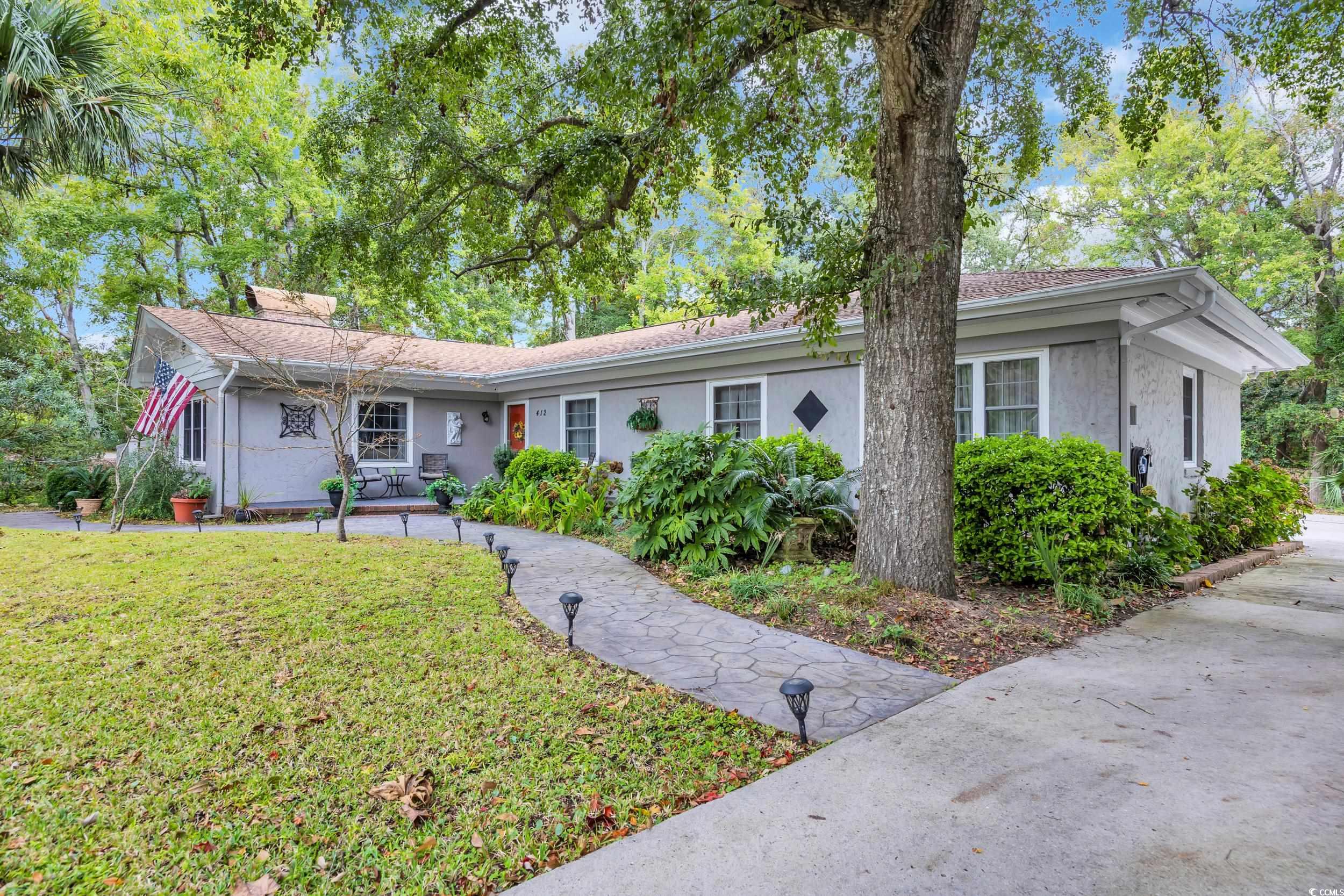 Ranch-style home with a front yard, stucco siding, and a chimney