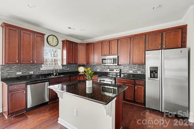 a kitchen with stainless steel appliances granite countertop a stove a sink dishwasher a refrigerator and a microwave