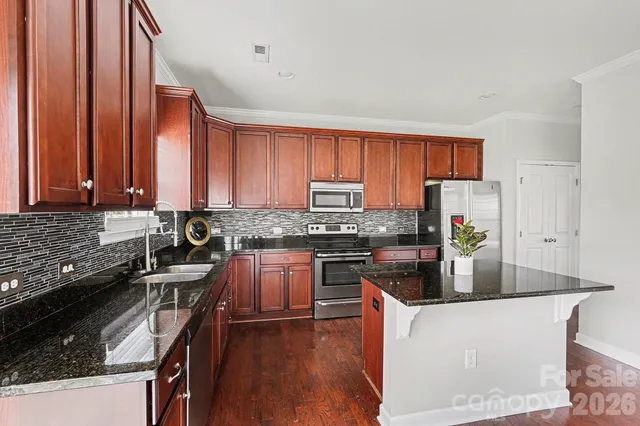 a kitchen with stainless steel appliances granite countertop a stove a sink dishwasher and a refrigerator with wooden floor