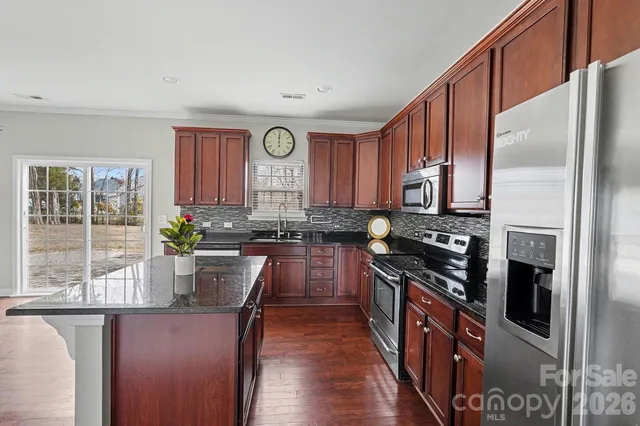 a kitchen with stainless steel appliances granite countertop a stove a sink and a refrigerator