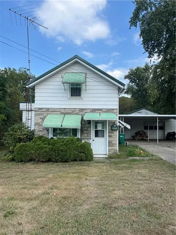 a view of a yard in front of a house with plants and large tree