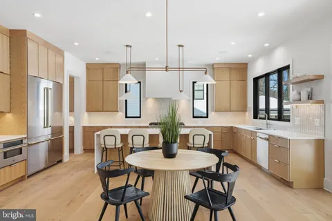 a kitchen with stainless steel appliances granite countertop a table chairs sink and cabinets