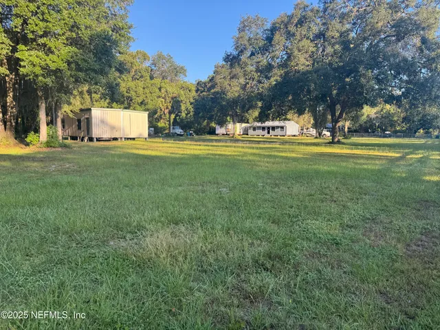 a view of swimming pool with lawn chairs and large trees