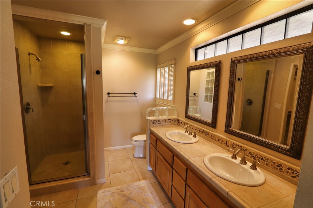 12885 Rain Shadow Road Victorville, CA 92395 - Photo 21 of 26 a bathroom with a double vanity sink and mirror with shower