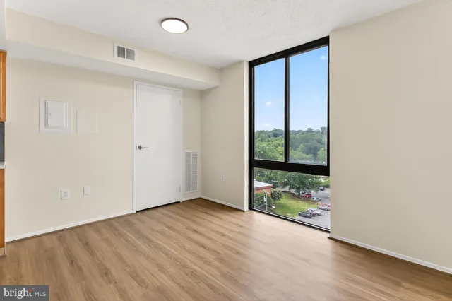 an empty room with wooden floor and windows