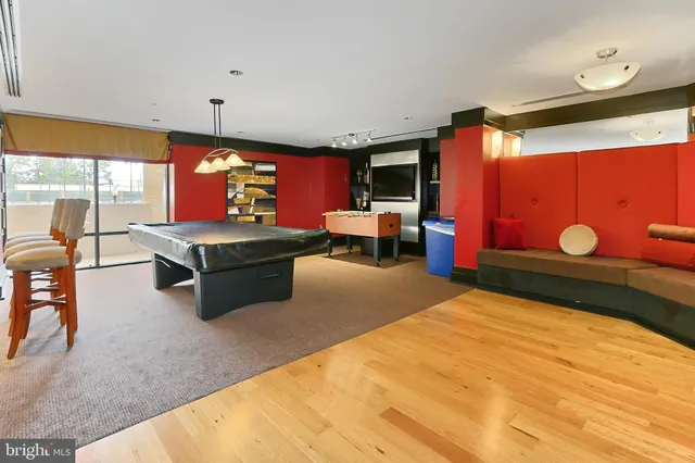 a living room with stainless steel appliances dining table wooden floor and a kitchen view