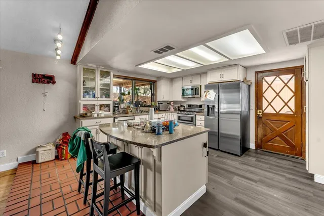 a kitchen with stainless steel appliances kitchen island granite countertop a table chairs in it and wooden floors