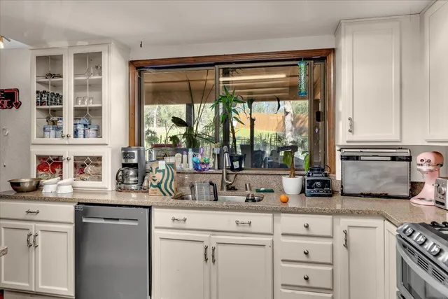 a kitchen with stainless steel appliances white cabinets and a large window