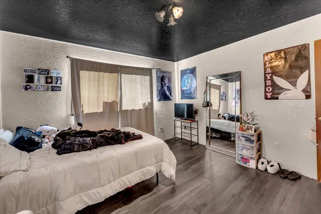 a bedroom with a bed a standing fan and a large window