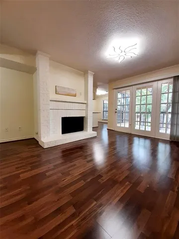 an empty room with wooden floor fireplace and windows