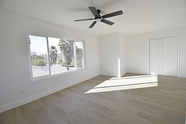 a view of empty room with wooden floor and fan
