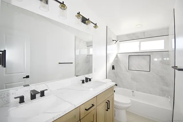 a bathroom with a granite countertop sink a toilet a mirror and shower