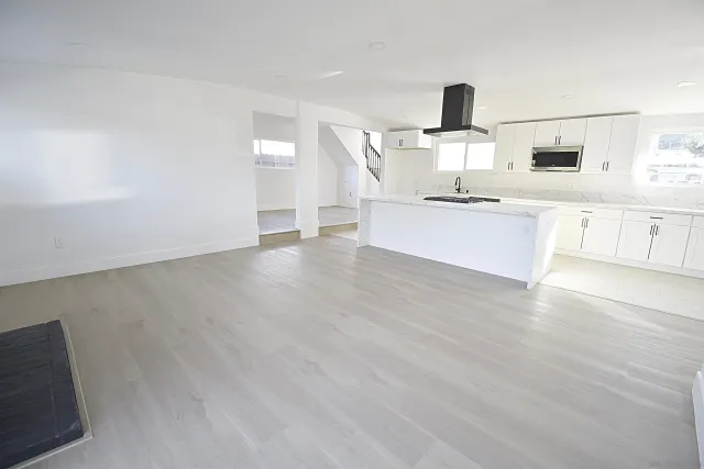 a large white kitchen with cabinets and wooden floor