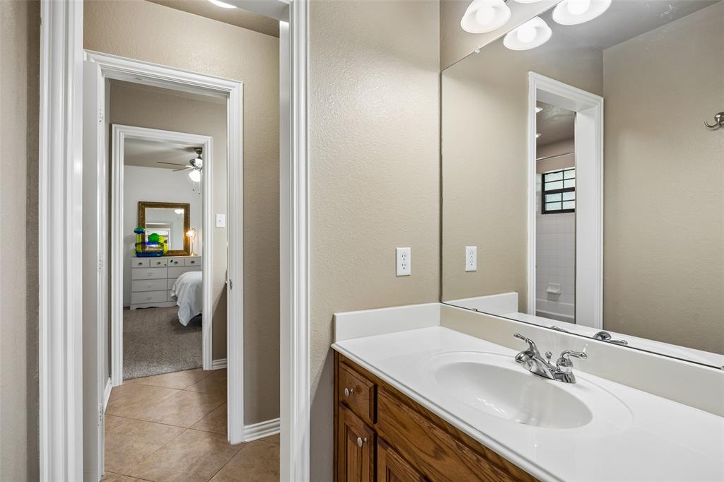 11211 Emerald Ranch Lane Forney, TX 75126 - Photo 30 of 35 Secondary Bathroom vanity featuring a white countertop with an integrated sink, chrome faucet, and wood cabinetry