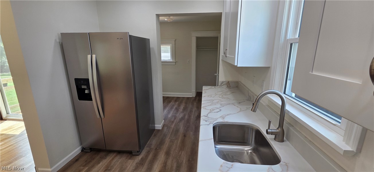 9964 East River Road Elyria, OH 44035 - Photo 15 of 45 Modern kitchen featuring a stainless steel refrigerator, white shaker-style cabinetry, and marble-look countertops with a matching backsplash
