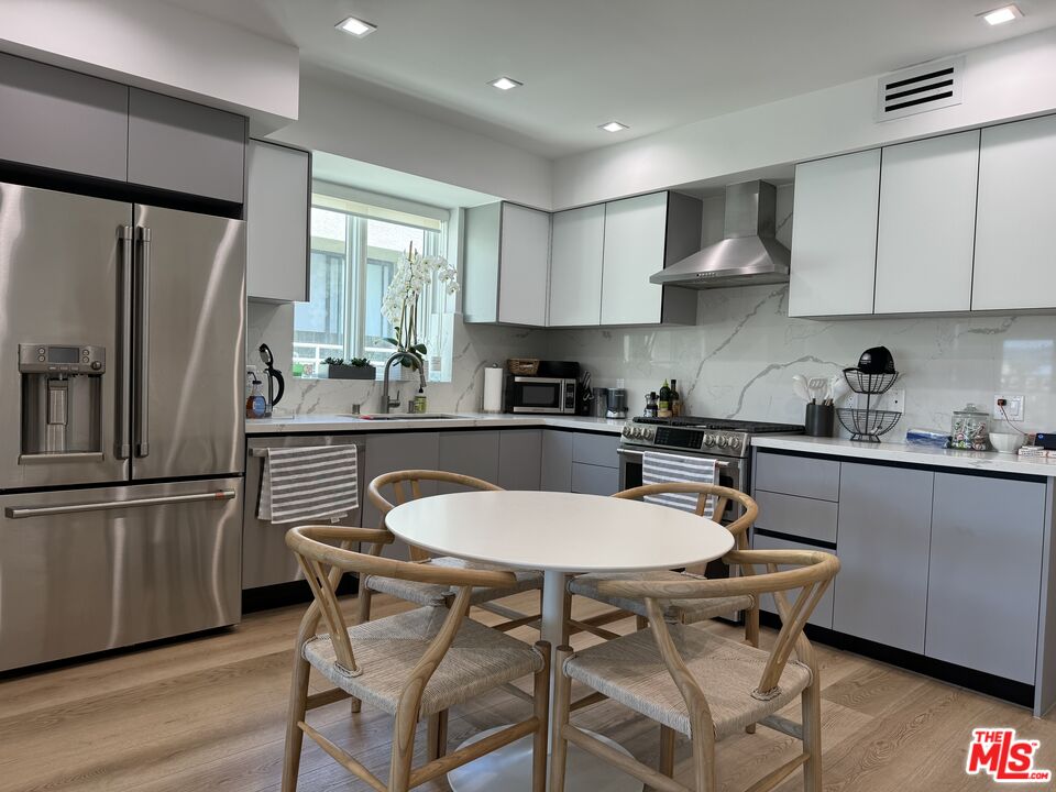 9842 Vidor Drive, Unit 402 Los Angeles, CA 90035 - Photo 19 of 23 a kitchen with stainless steel appliances granite countertop a sink a stove a refrigerator cabinets and a dining table with wooden floor
