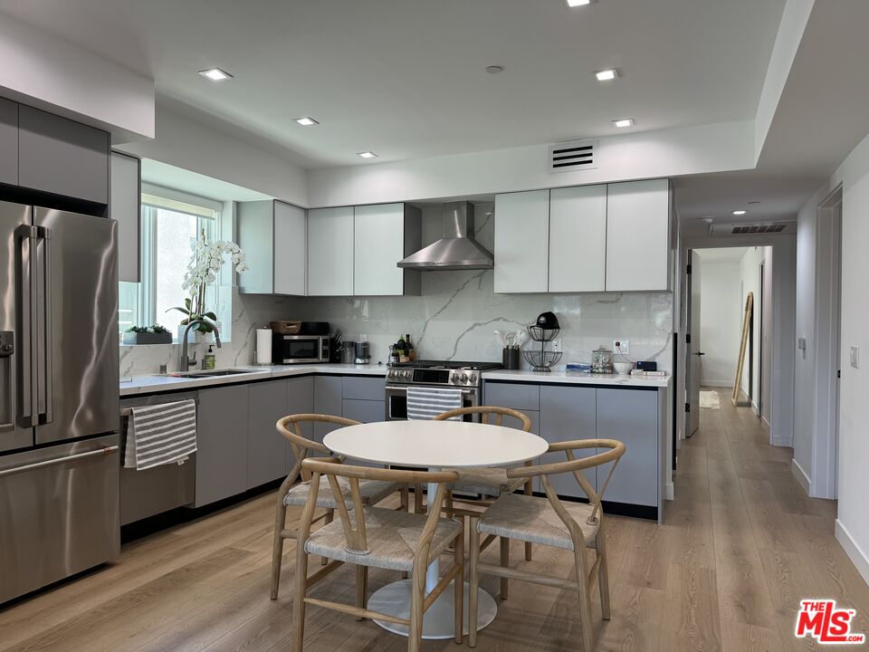 9842 Vidor Drive, Unit 402 Los Angeles, CA 90035 - Photo 3 of 23 a kitchen with stainless steel appliances granite countertop a sink a stove a refrigerator and white cabinets with wooden floor