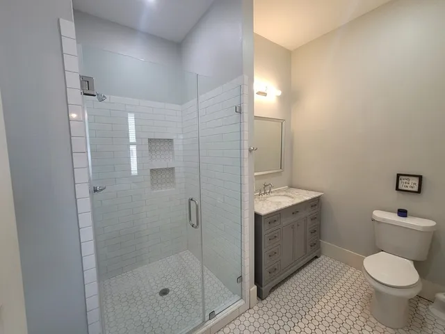 a bathroom with a granite countertop toilet a sink and a mirror