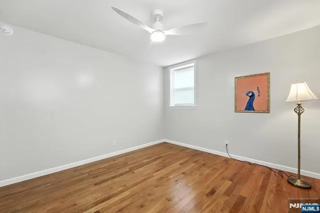 an empty room with wooden floor and fan