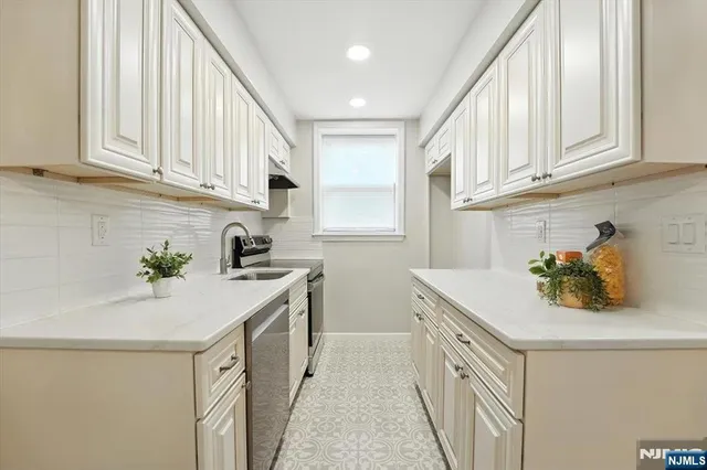 a kitchen with a sink dishwasher and white cabinets with wooden floor