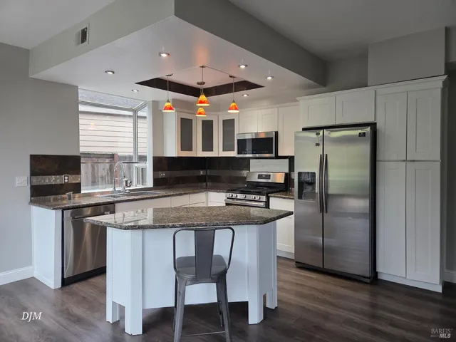 a kitchen with stainless steel appliances granite countertop a stove a sink a refrigerator and a microwave