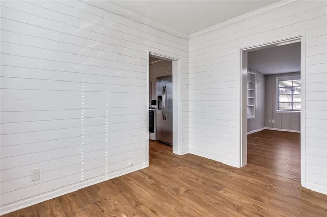 a view of an empty room with window and wooden floor