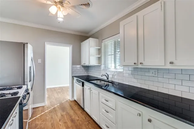 a kitchen with granite countertop a sink a counter space appliances and cabinets