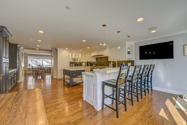 9699 Bypass Road, Unit 5 Alta, UT 84092 - Photo 30 of 54 Open-concept kitchen featuring wood-finish flooring, recessed lighting, a large island with seating, white cabinetry, and a separate dining area with a prominent window