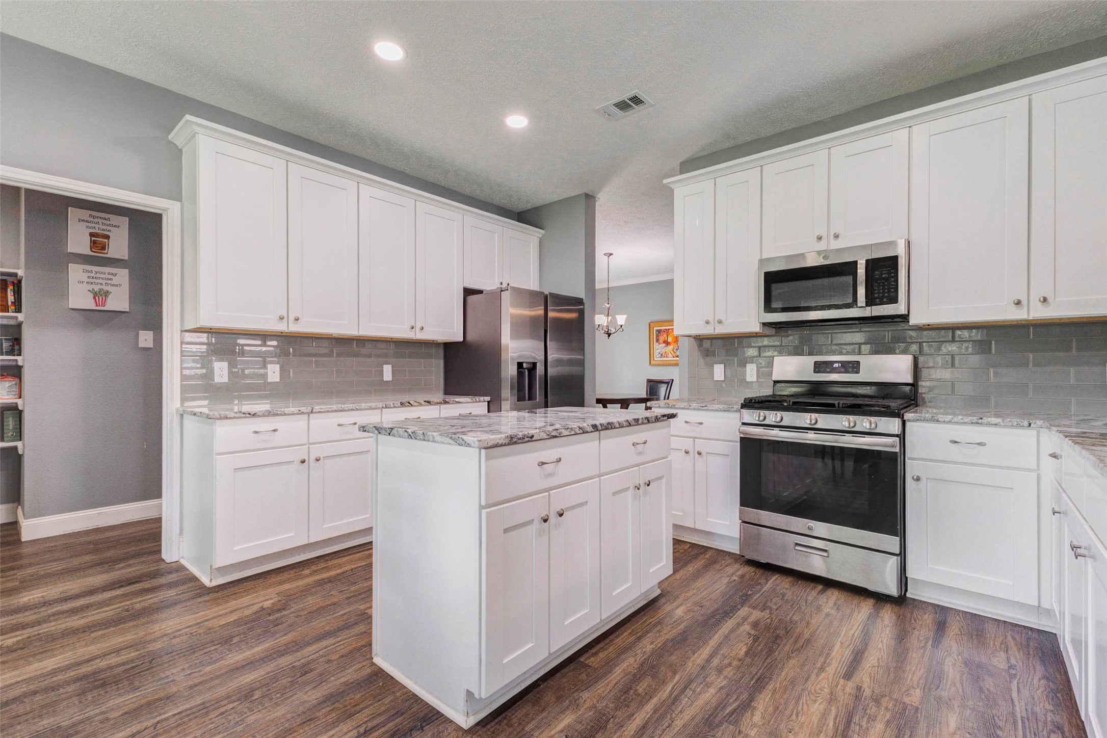 9215 Landry Boulevard Spring, TX 77379 - Photo 11 of 42 Welcome to the heart of the home, where this beautifully updated kitchen showcases granite countertops, a stylish subway tile backsplash, stainless steel appliances, a gas range, built in microwave, and an oversized island with additional storage and prep space.