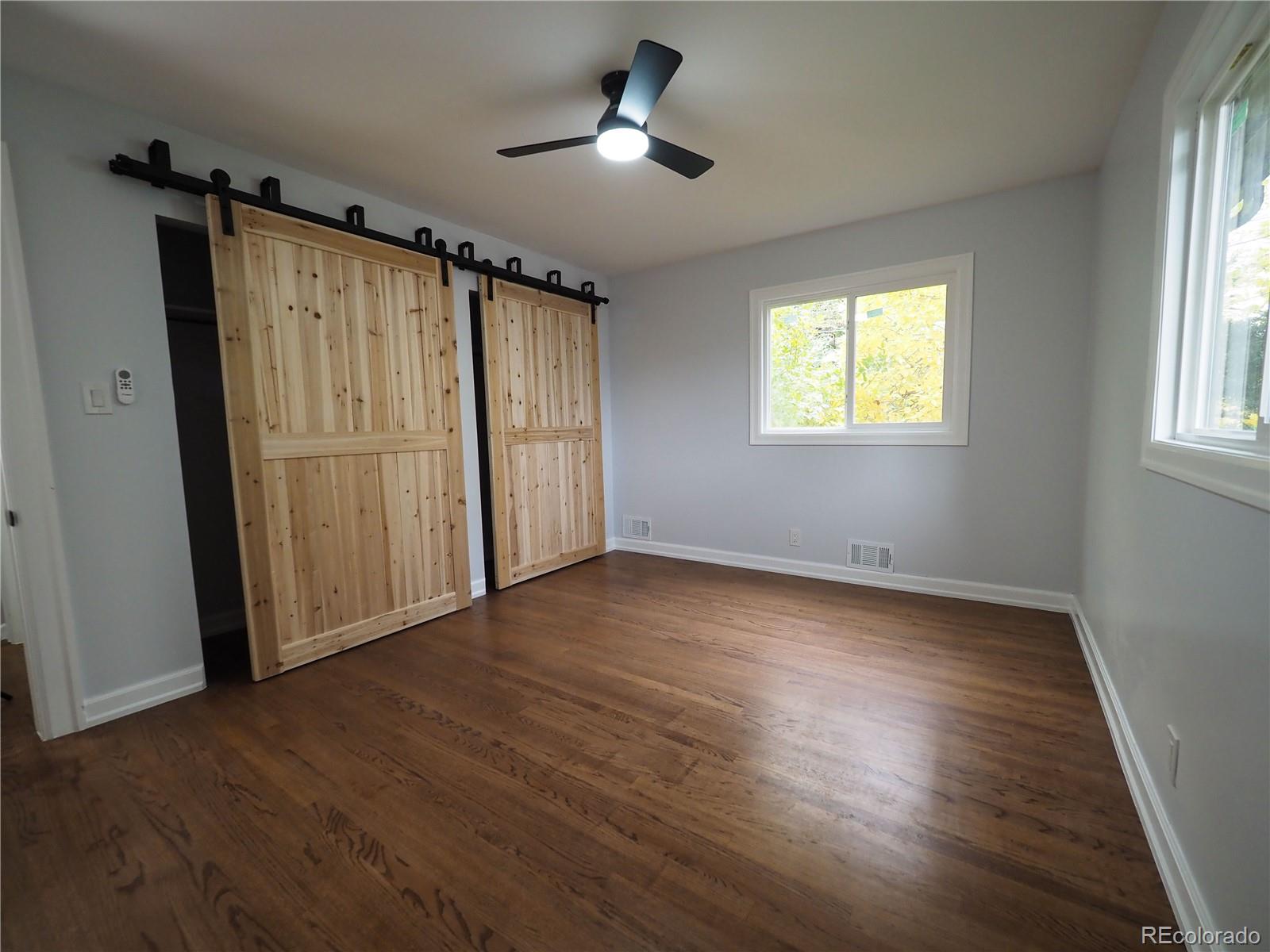 6751 South Downing Circle West Centennial, CO 80122 - Photo 12 of 34 an empty room with wooden floor ceiling fan and windows