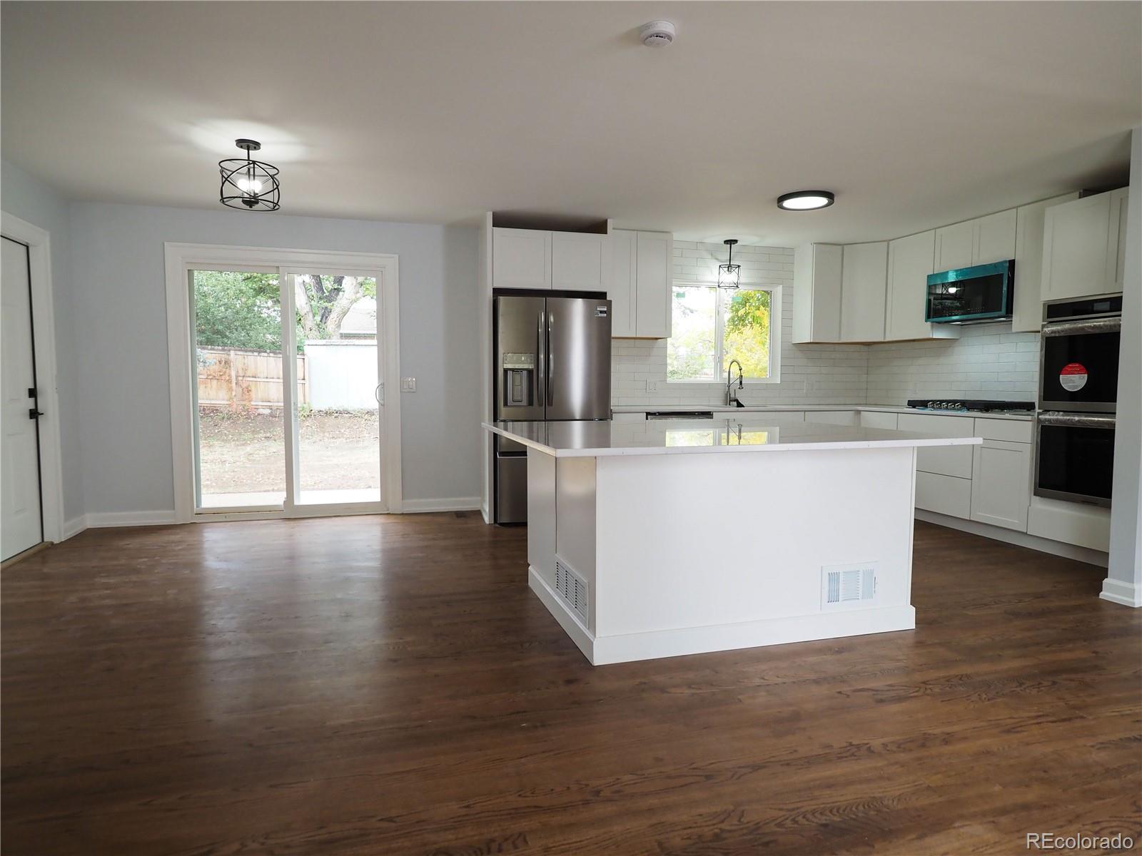 6751 South Downing Circle West Centennial, CO 80122 - Photo 2 of 34 a large kitchen with stainless steel appliances granite countertop a stove a sink dishwasher a microwave oven and a dining table with wooden floor