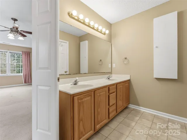 an empty room with chandelier fan and windows