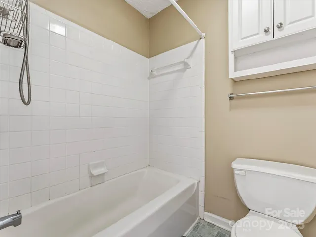 an empty room with chandelier fan and windows