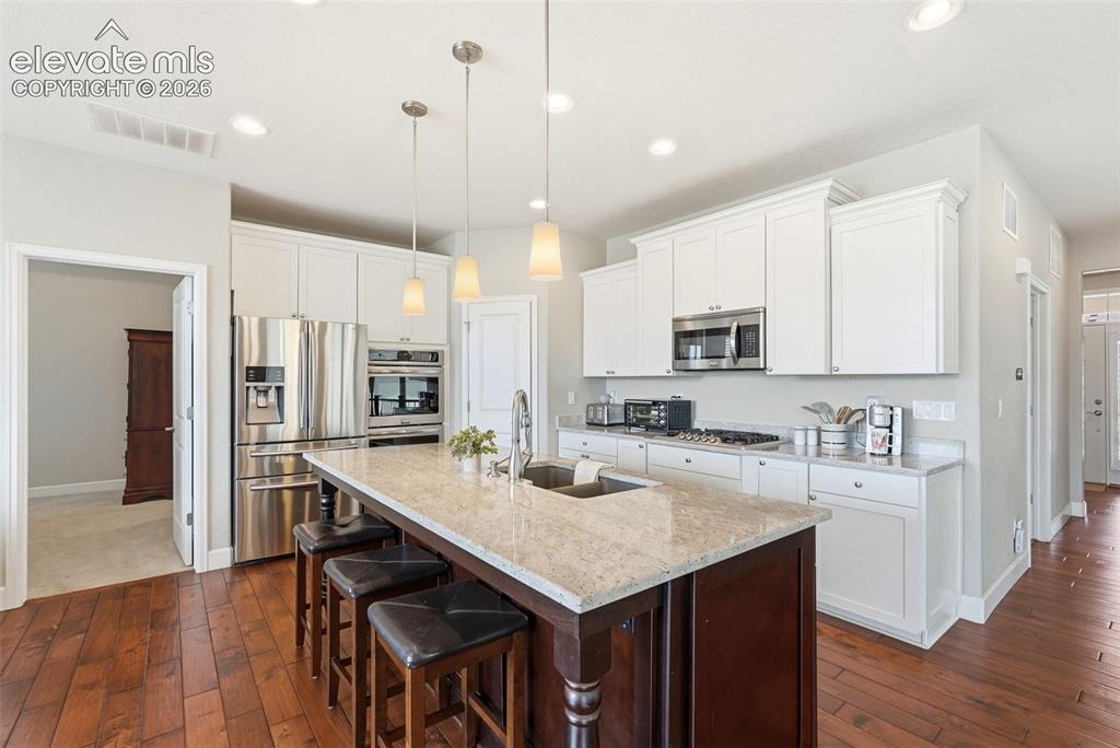 1394 Promontory Bluff View Colorado Springs, CO 80921 - Photo 6 of 47 a kitchen with stainless steel appliances granite countertop a table chairs stove microwave and cabinets
