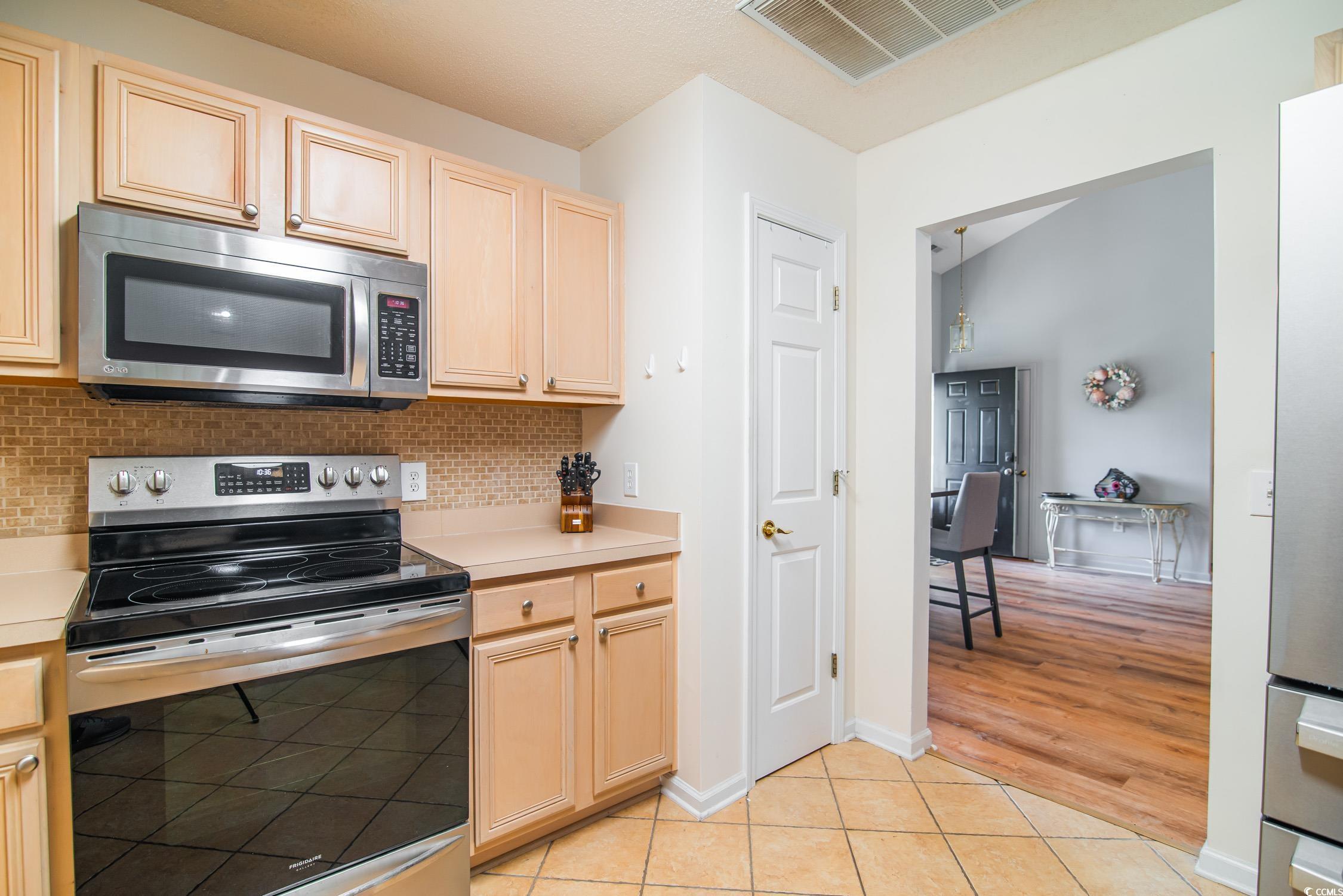 1052 Vestry Drive Murrells Inlet, SC 29576 - Photo 19 of 40 Kitchen featuring stainless steel appliances, light countertops, light tile patterned flooring, backsplash, and light brown cabinets
