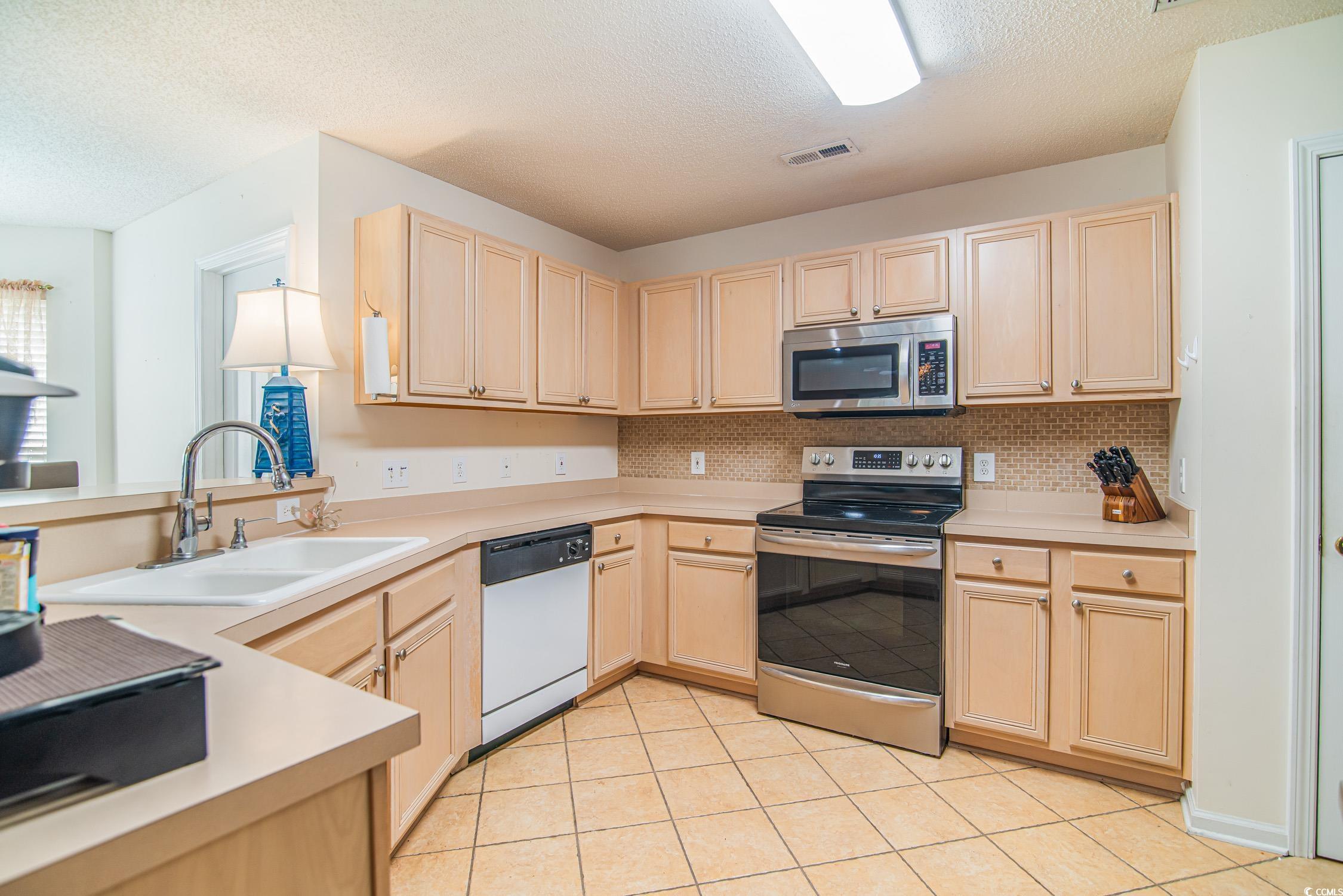 1052 Vestry Drive Murrells Inlet, SC 29576 - Photo 20 of 40 Kitchen with light brown cabinetry, stainless steel appliances, a textured ceiling, decorative backsplash, and light countertops