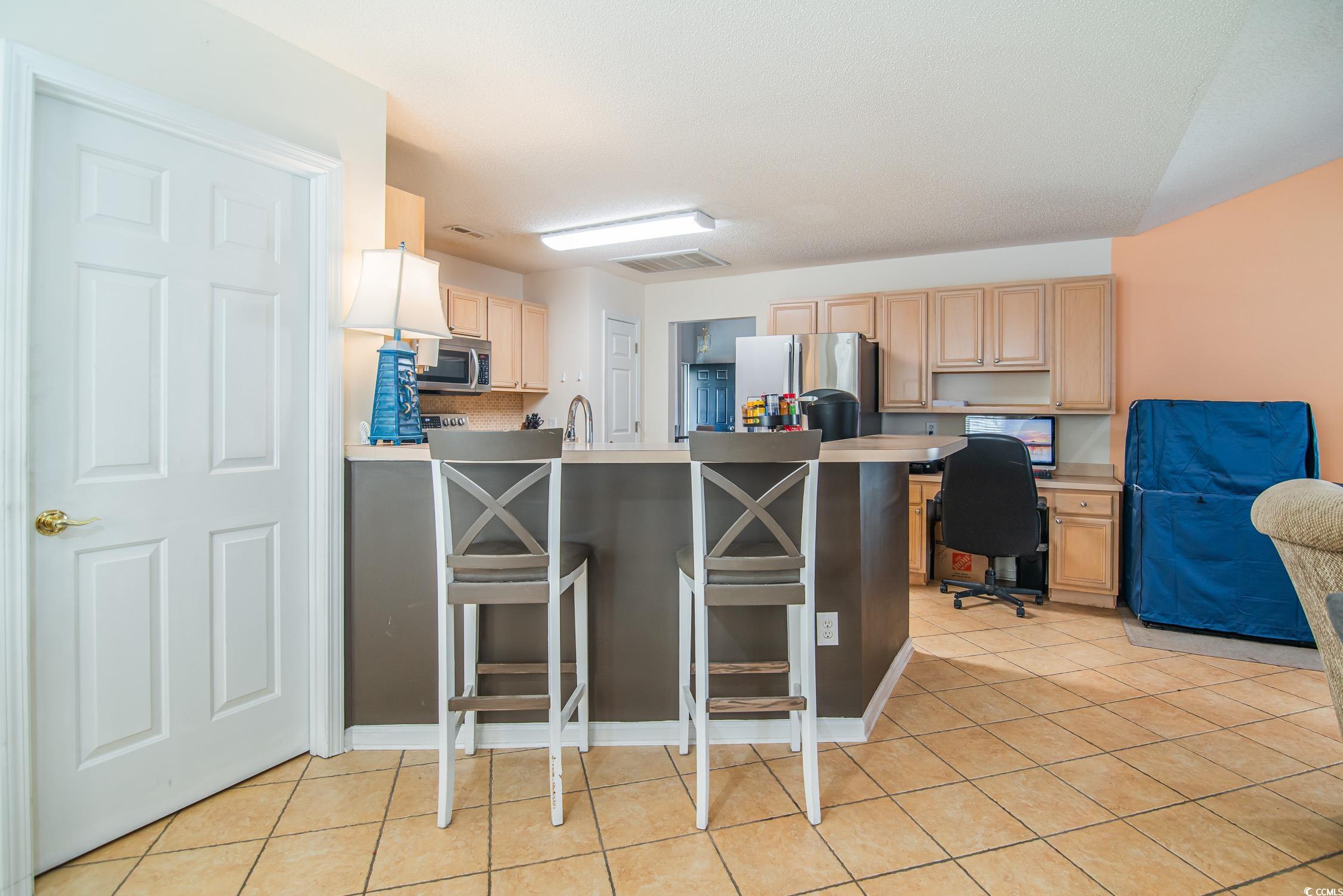1052 Vestry Drive Murrells Inlet, SC 29576 - Photo 21 of 40 Kitchen featuring a peninsula, light brown cabinetry, light tile patterned flooring, stainless steel appliances, and light countertops