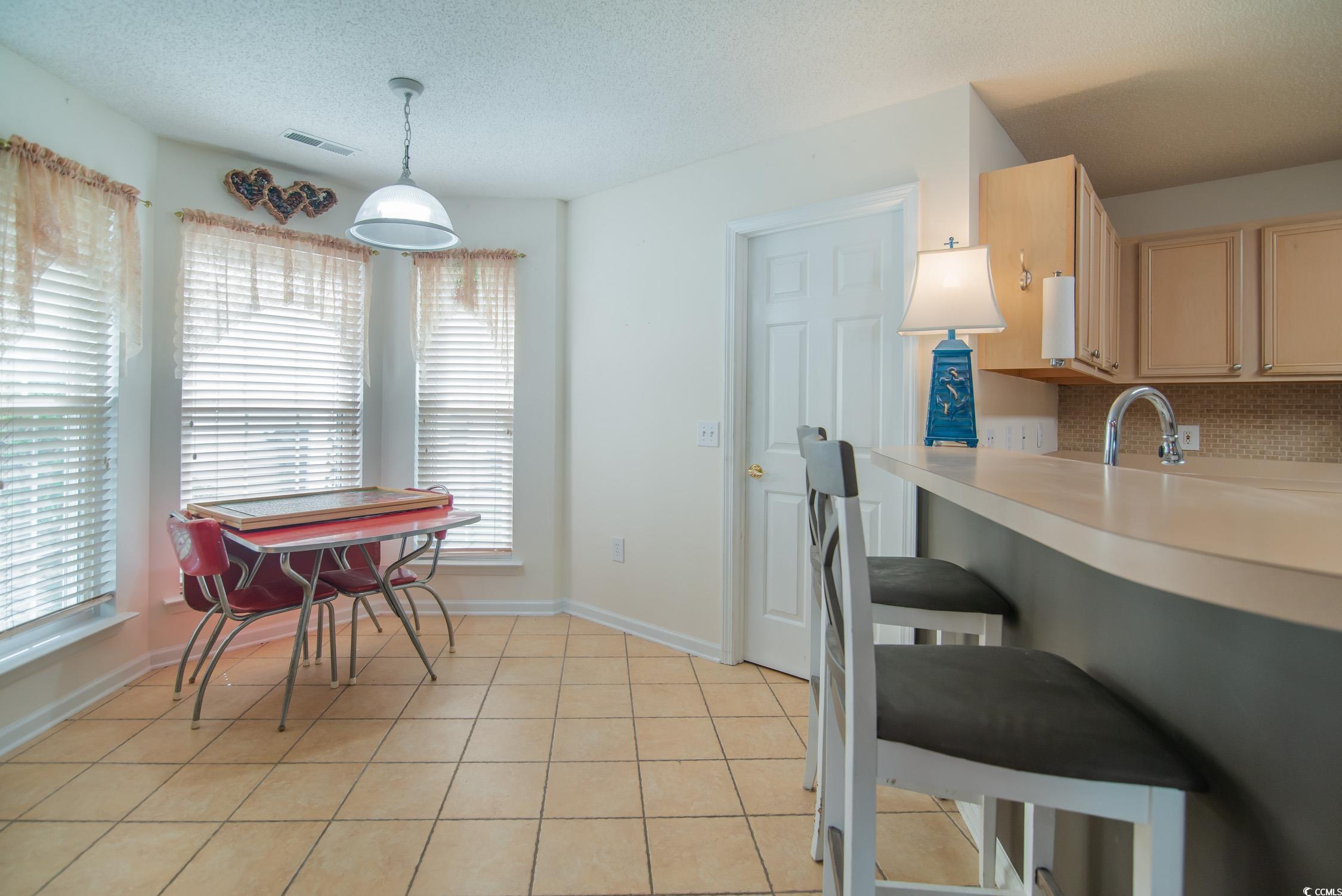 1052 Vestry Drive Murrells Inlet, SC 29576 - Photo 22 of 40 Kitchen with light countertops, pendant lighting, light brown cabinets, backsplash, and light tile patterned flooring