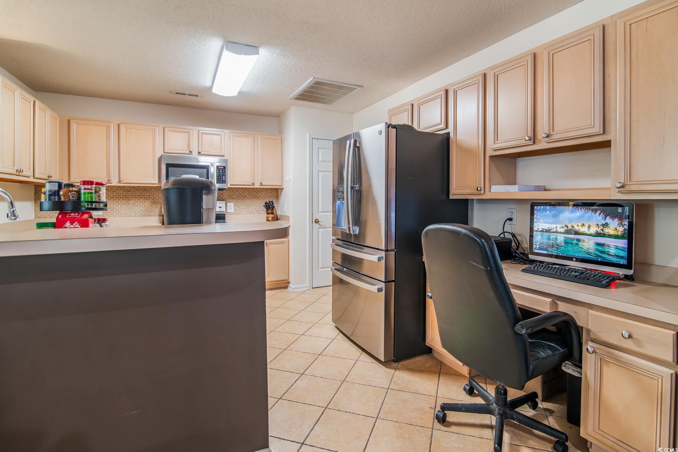 1052 Vestry Drive Murrells Inlet, SC 29576 - Photo 23 of 40 Kitchen featuring built in study area, stainless steel appliances, light brown cabinets, light countertops, and a textured ceiling