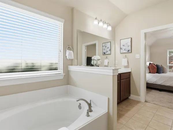 a en suite spacious bathroom with a tub double vanity and window