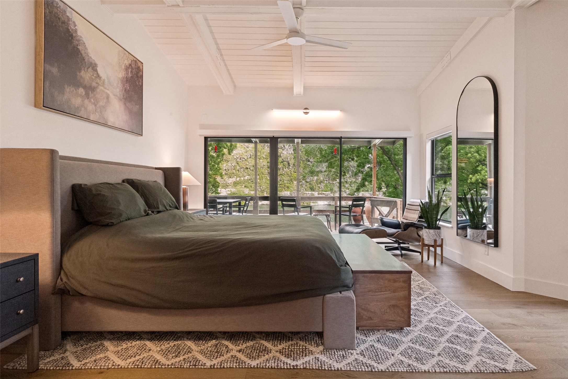 303 Lago Verde Road Austin, TX 78734 - Photo 18 of 39 Natural light floods this primary bedroom through a wall of windows, revealing lush outdoor views and a private deck.