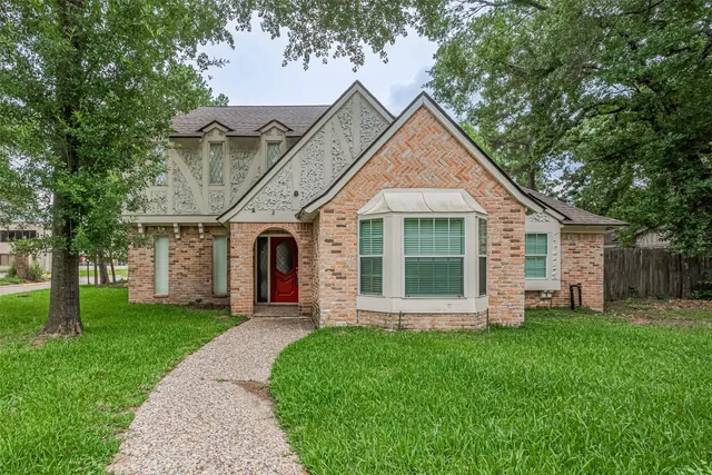a view of a house with a yard and large tree