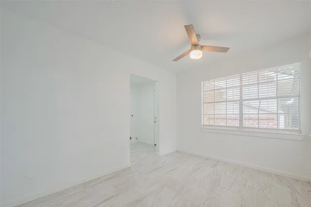 an empty room with chandelier fan and windows