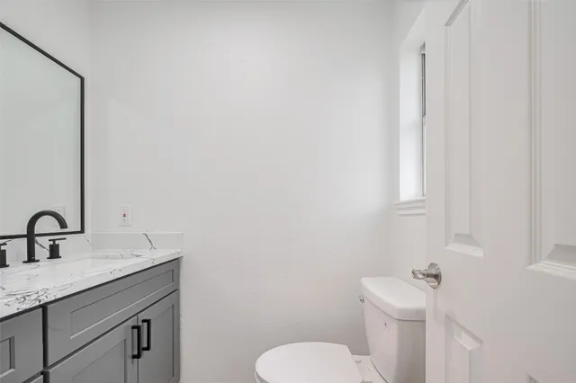 a bathroom with a granite countertop sink toilet and mirror